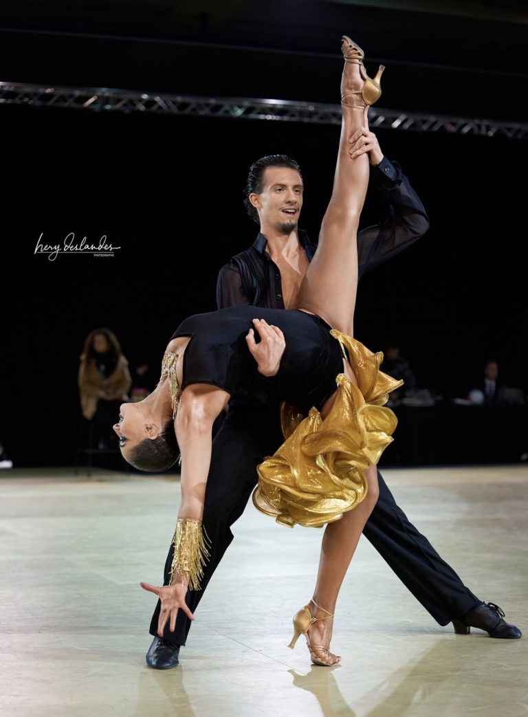 A dance couple mid-lift in a black and gold outfit