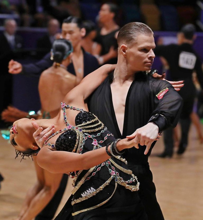 A competitive couple in a dramatic Standard dance position