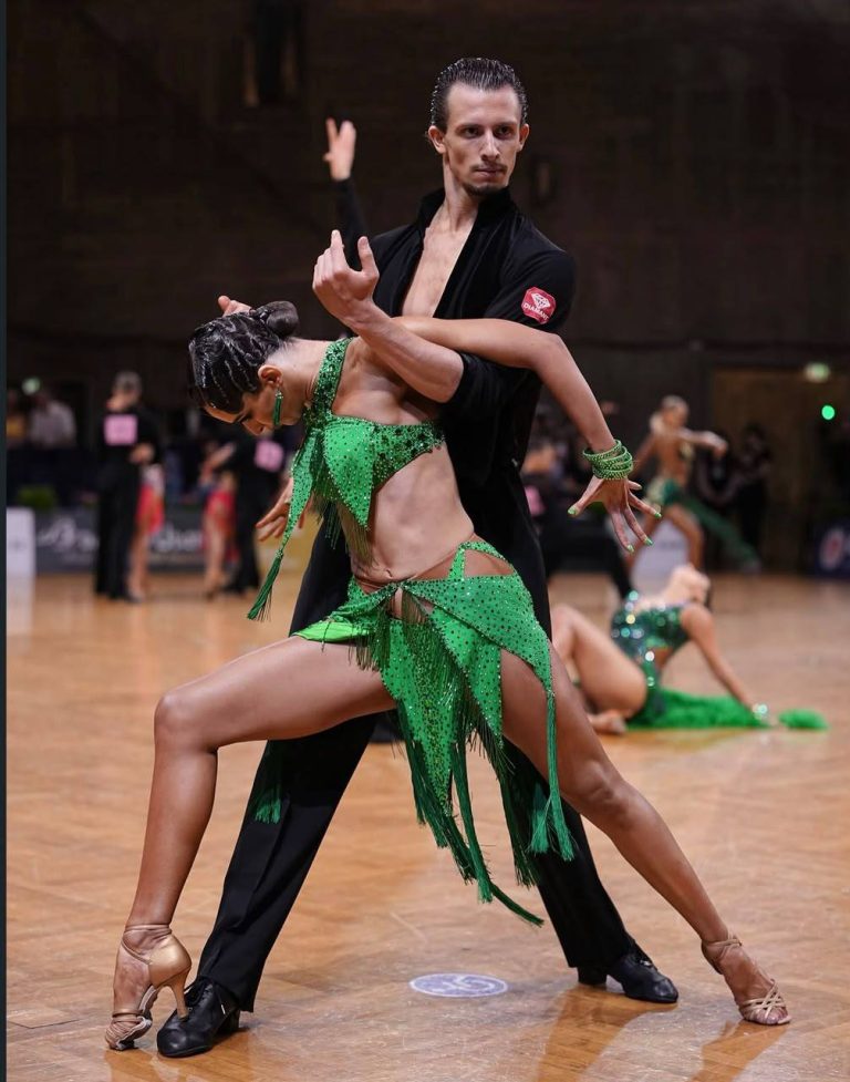A dance couple in a green competition outfit performing